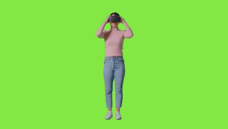 Ganzkörperaufnahme-Einer-Frau,-Die-Ein-Virtual-Reality-Headset-Trägt-Und-Vor-Grünem-Studiohintergrund-Interagiert
